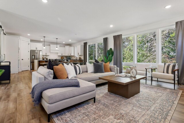 living room featuring light wood finished floors, a barn door, and recessed lighting