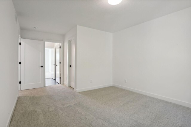 unfurnished room featuring light carpet and baseboards