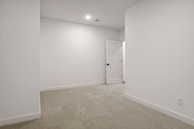 spare room with baseboards, recessed lighting, and light colored carpet