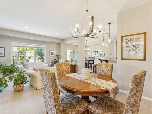 dining space featuring sink, a chandelier, and light carpet