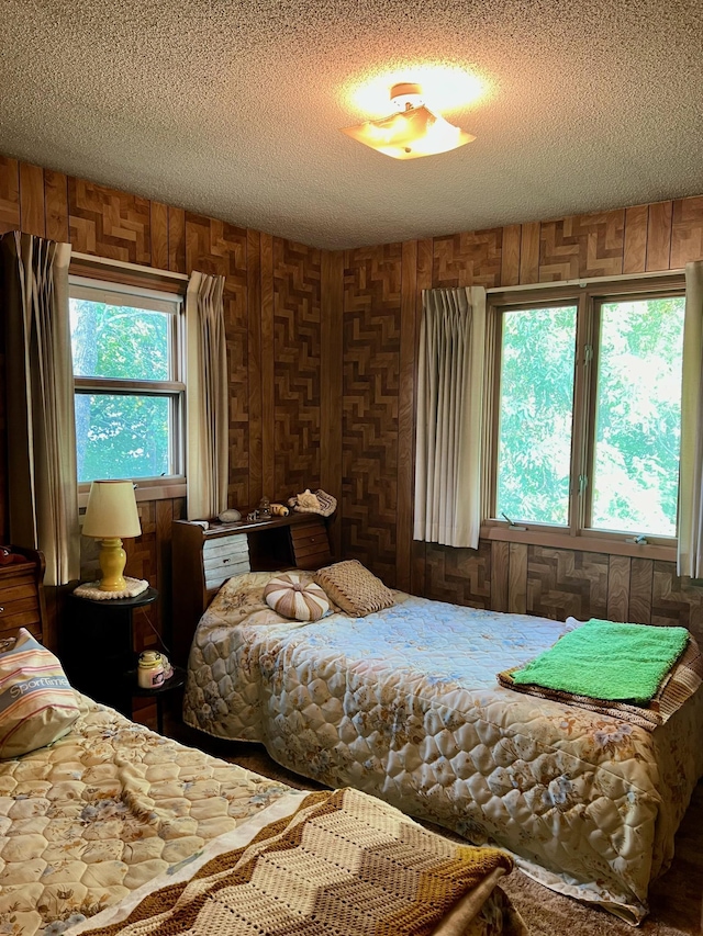 bedroom featuring a textured ceiling and wooden walls