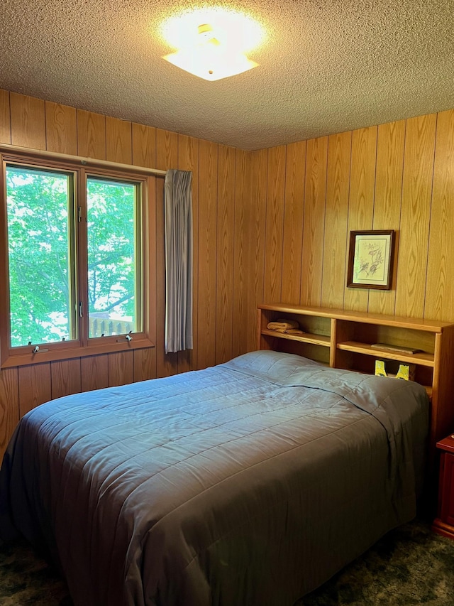 bedroom with a textured ceiling and wood walls