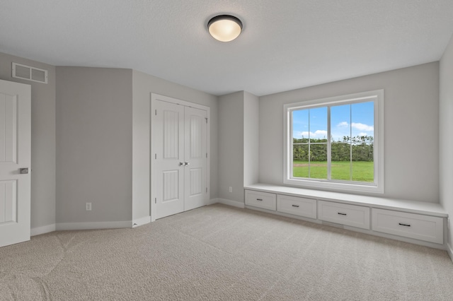 unfurnished bedroom featuring light carpet and a closet