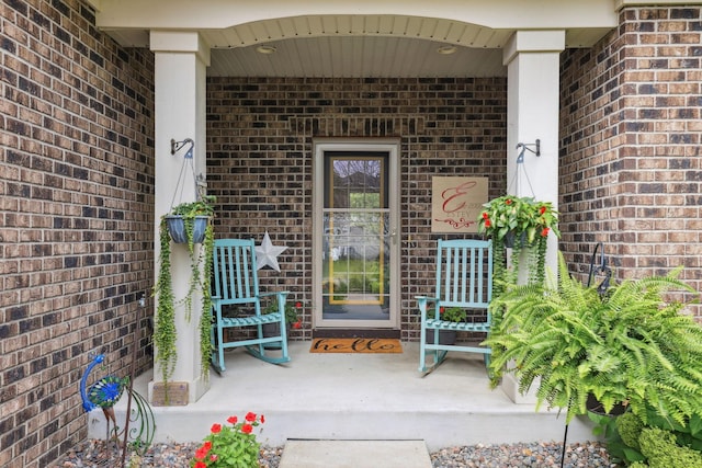 entrance to property featuring brick siding and covered porch