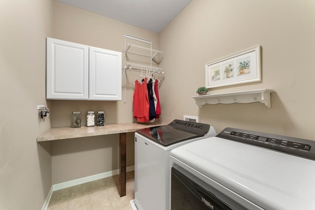 washroom featuring light tile patterned floors, baseboards, cabinet space, a textured ceiling, and washing machine and dryer