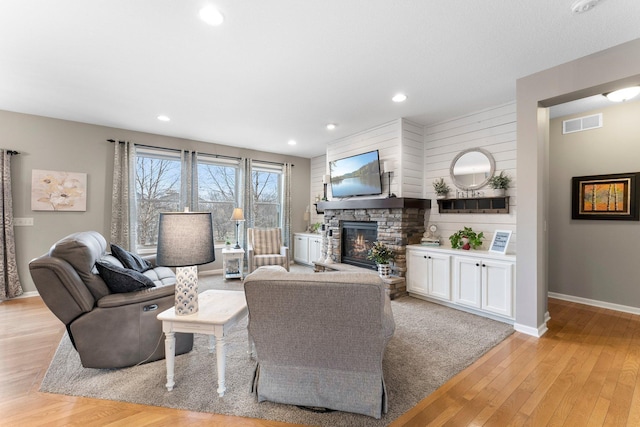 living area with baseboards, a fireplace, visible vents, and light wood-type flooring