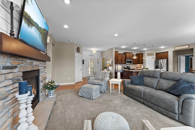 living area with recessed lighting, baseboards, and a stone fireplace