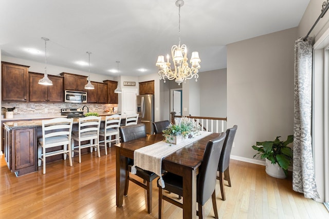 dining room with an inviting chandelier, light wood-style flooring, and baseboards