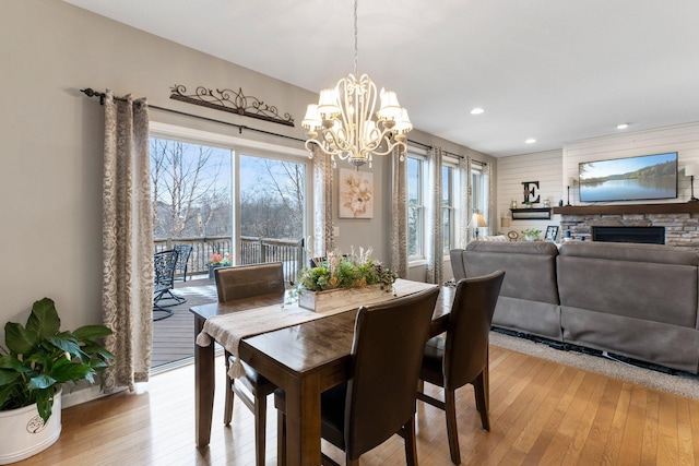 dining room featuring recessed lighting, a notable chandelier, a fireplace, and light wood finished floors