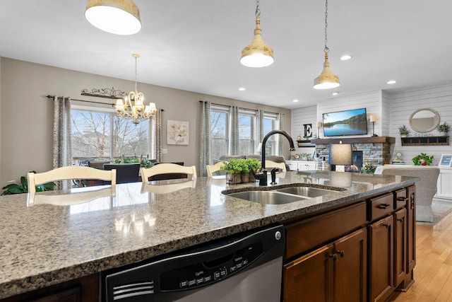 kitchen featuring a sink, dark stone counters, stainless steel dishwasher, and pendant lighting