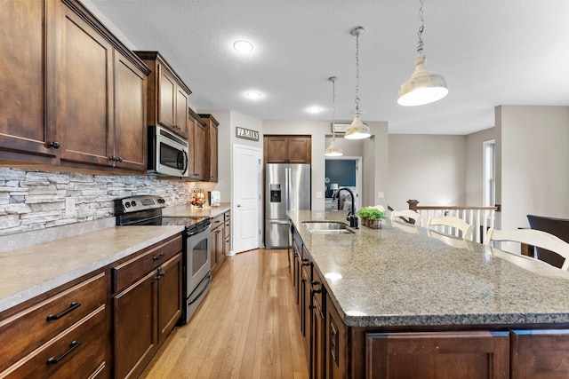 kitchen with a sink, a spacious island, appliances with stainless steel finishes, a breakfast bar area, and decorative backsplash