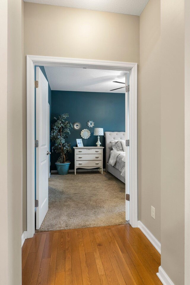 hall with baseboards and wood finished floors