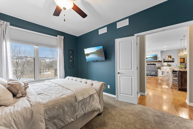 bedroom with visible vents, light wood-style flooring, a ceiling fan, and baseboards