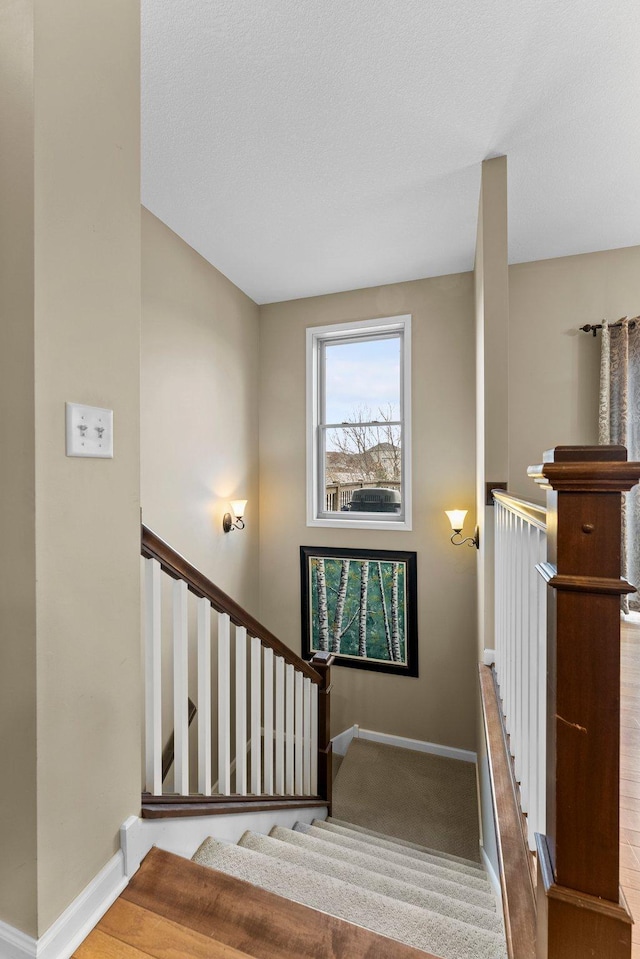 staircase with baseboards and carpet floors