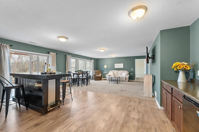 dining space featuring visible vents, light wood-style floors, baseboards, and a textured ceiling