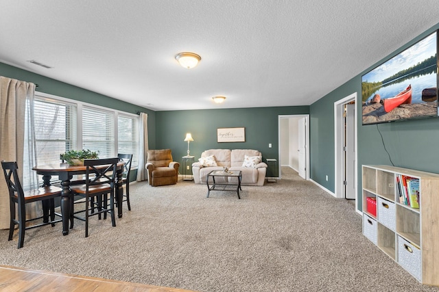 living area featuring visible vents, baseboards, a textured ceiling, and carpet flooring