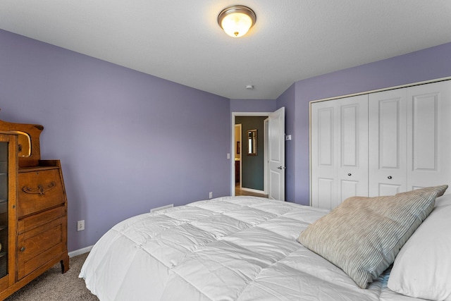 carpeted bedroom with a closet and baseboards