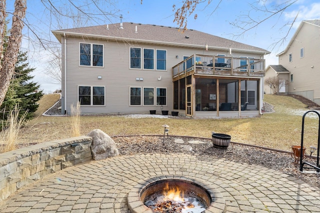 rear view of property with a patio, a lawn, a sunroom, and an outdoor fire pit