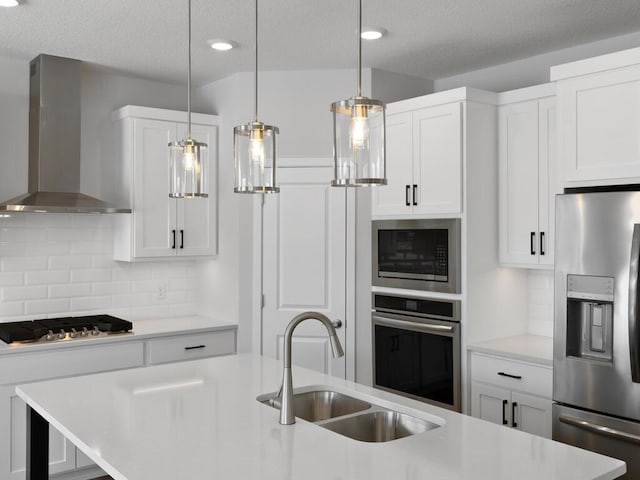 kitchen featuring sink, appliances with stainless steel finishes, tasteful backsplash, white cabinets, and wall chimney exhaust hood