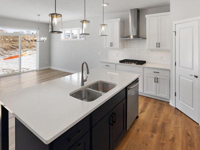 kitchen featuring sink, a center island with sink, dishwasher, wall chimney range hood, and white cabinets