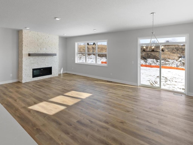 unfurnished living room featuring dark hardwood / wood-style floors, plenty of natural light, and a stone fireplace