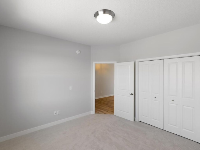 unfurnished bedroom featuring light colored carpet and a closet