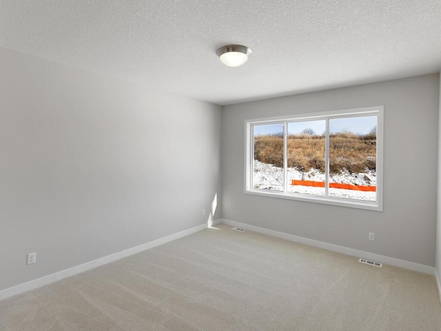 carpeted empty room with a textured ceiling