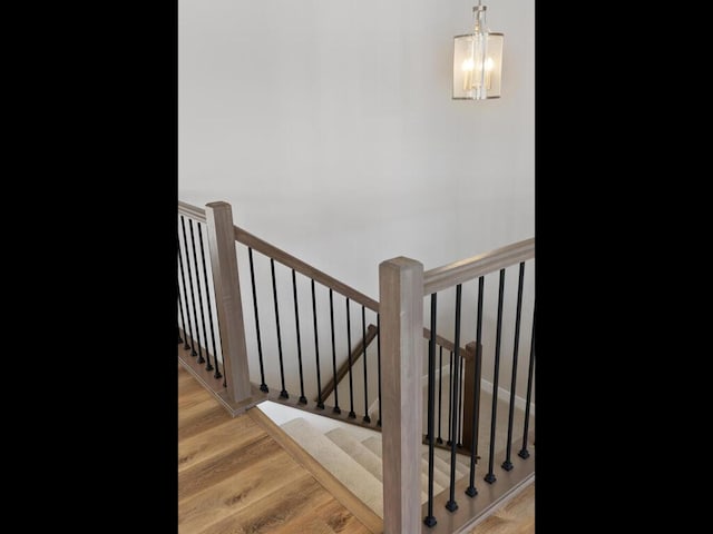 stairway with hardwood / wood-style flooring and a chandelier