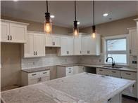 kitchen featuring light stone countertops, white cabinetry, hanging light fixtures, and a kitchen island