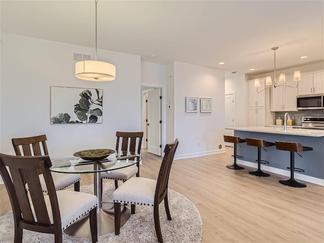 dining area featuring light hardwood / wood-style floors, sink, and a notable chandelier