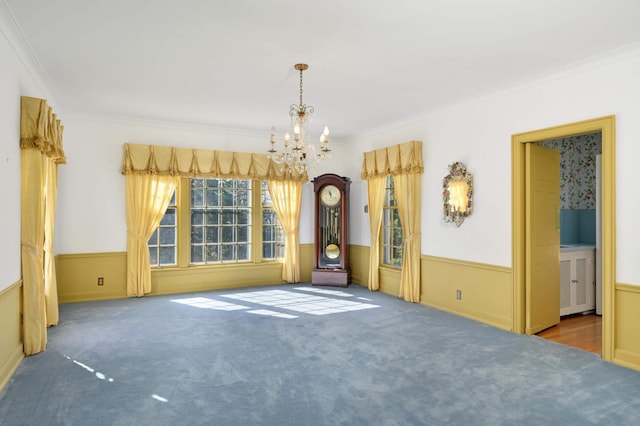 carpeted empty room featuring ornamental molding and a chandelier