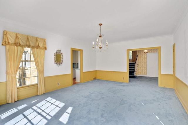 unfurnished room featuring an inviting chandelier, ornamental molding, and carpet flooring