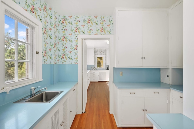 kitchen with sink, white cabinets, and light hardwood / wood-style flooring