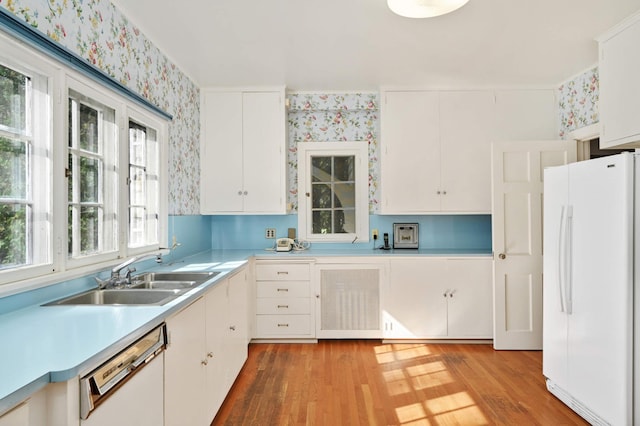 kitchen with sink, white cabinetry, white appliances, and light hardwood / wood-style floors