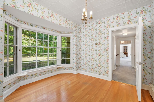 unfurnished room with a notable chandelier, hardwood / wood-style flooring, and plenty of natural light