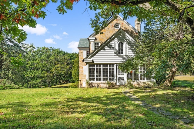 rear view of house featuring a sunroom and a lawn