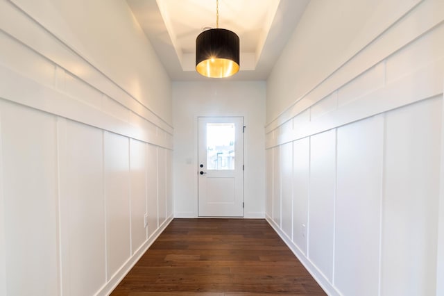 doorway with dark hardwood / wood-style floors and a tray ceiling