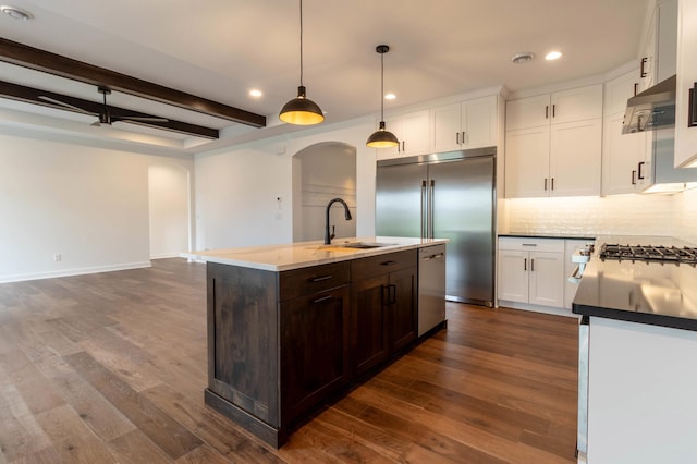 kitchen with an island with sink, beam ceiling, sink, and dark hardwood / wood-style flooring