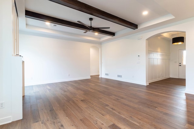 spare room featuring a tray ceiling, dark wood-type flooring, ceiling fan, and beam ceiling