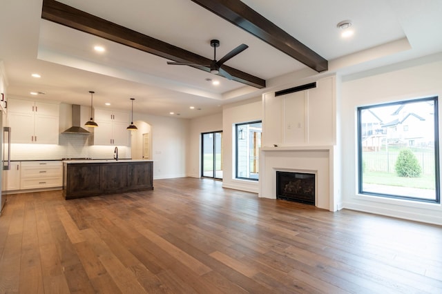 kitchen with hanging light fixtures, wall chimney exhaust hood, dark hardwood / wood-style floors, and white cabinets