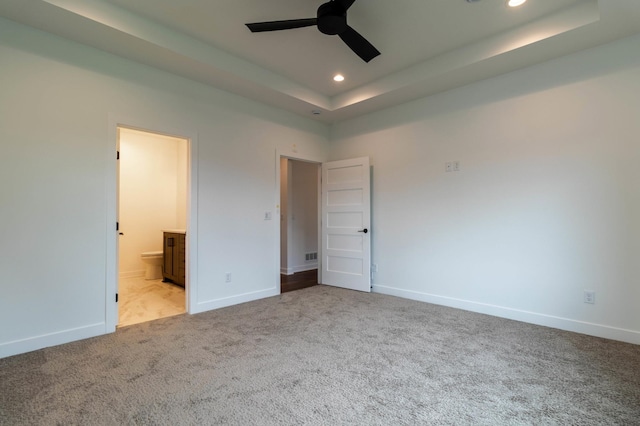 unfurnished bedroom featuring light carpet, a raised ceiling, ceiling fan, and ensuite bathroom