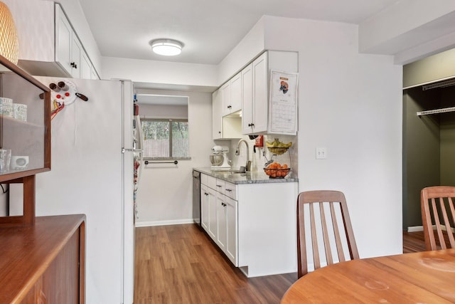 kitchen featuring dark stone countertops, white cabinets, white fridge, hardwood / wood-style flooring, and sink