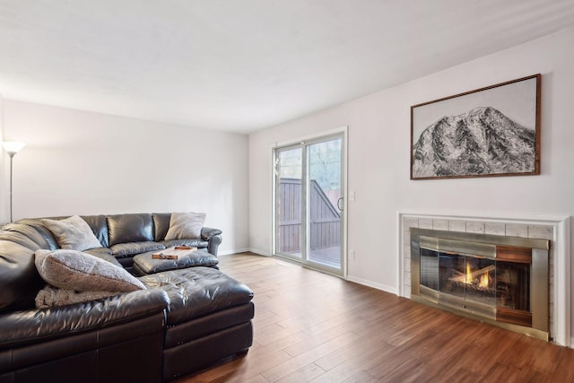 living room with wood-type flooring and a tile fireplace