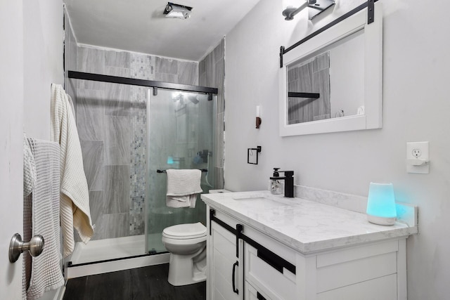 bathroom with walk in shower, vanity, toilet, and wood-type flooring