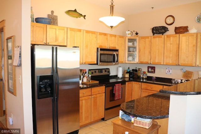 kitchen featuring pendant lighting, dark stone counters, light tile patterned flooring, kitchen peninsula, and stainless steel appliances