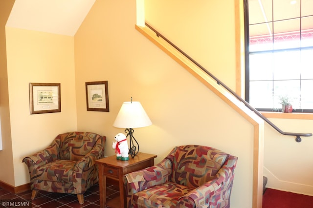 sitting room with dark tile patterned floors and vaulted ceiling