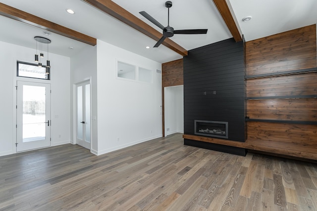 unfurnished living room with beam ceiling, a fireplace, wood-type flooring, and a towering ceiling