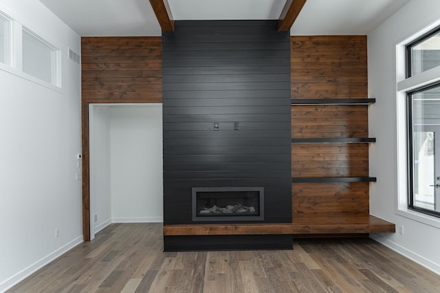 details with hardwood / wood-style floors, beam ceiling, wooden walls, and a large fireplace