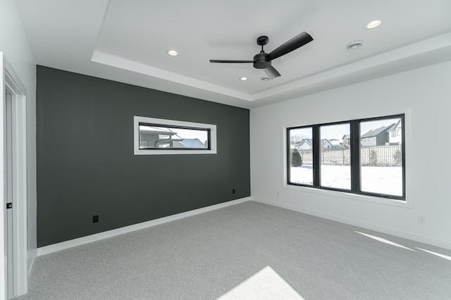 spare room with light carpet, a raised ceiling, and ceiling fan