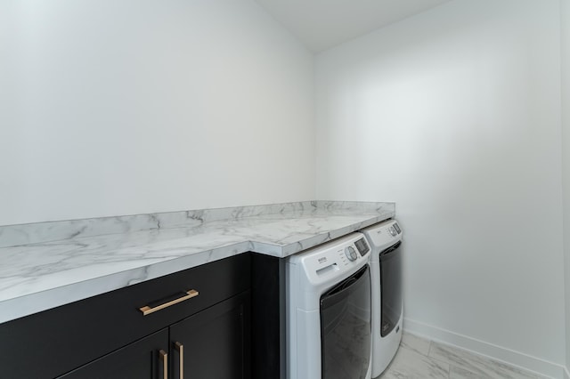 clothes washing area with washer and clothes dryer and cabinets